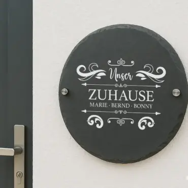 Schilder personalisiert: rundes Schieferschild mit Familiennamen an der Hauswand