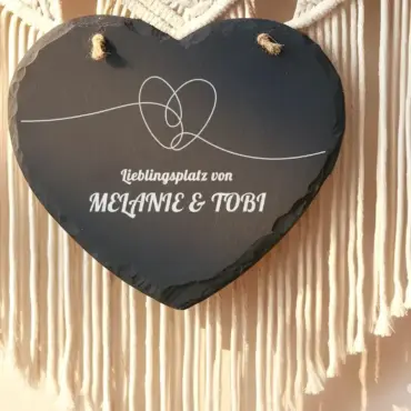 Schieferherz personalisiert mit zwei Namen an einer Makramee-Wand