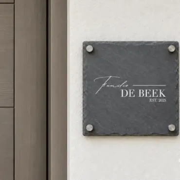 Klingelschild aus Schiefer: quadratisches Namensschild „Familie DE BEEK“ auf Abstandshaltern neben der Haustür