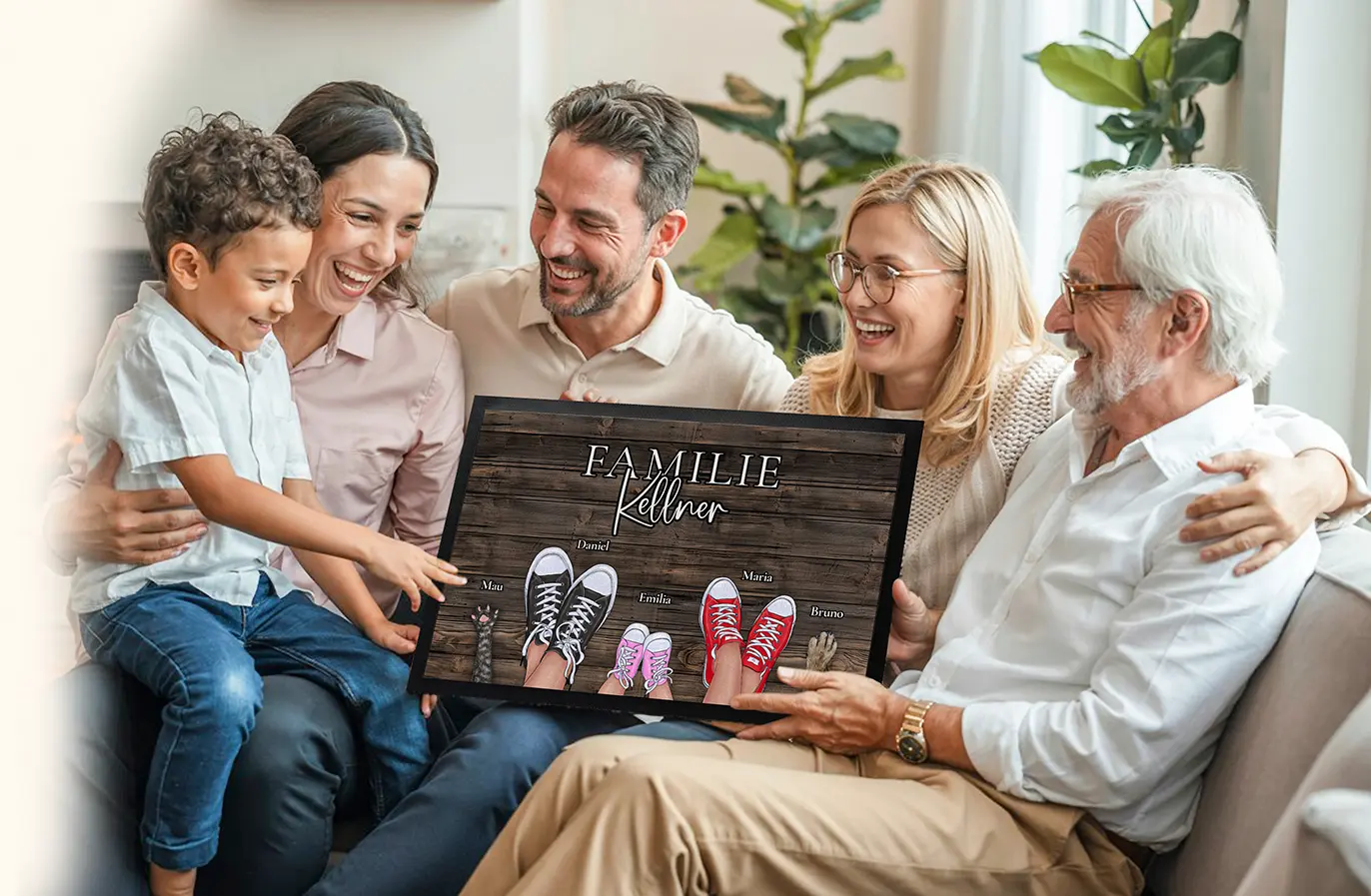 Familie auf dem Sofa hält eine personalisierte Fußmatte mit ihrem Familiennamen